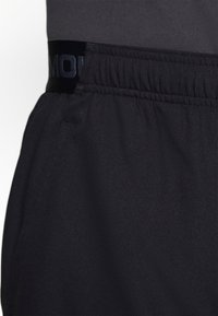 Schwarze Sportshorts mit einem elastischen Bund und subtiler Textur. Enthält ein Logo-Band am Bund, das für Komfort und Bewegungsfreiheit entwickelt wurde.