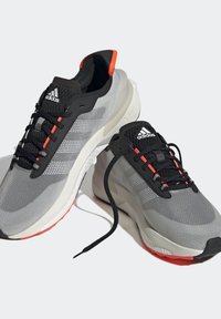 Chaussures de course Adidas gris et noir avec semelles blanches, accents orange, lacets noirs et tige en mesh respirant.