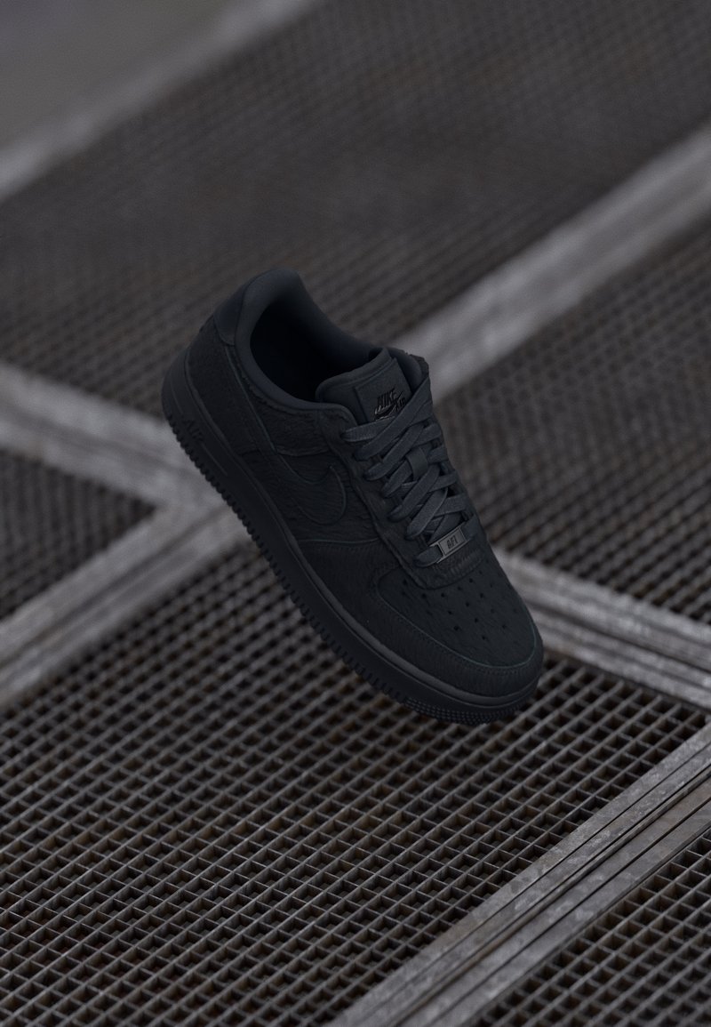 Sneaker Nike Air Force 1 preto com sobreposições de couro e texturizadas, com bico arredondado, atacadores planos e sola de borracha.