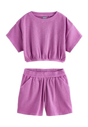 Dvojdielny súbor s rebrovanou textúrou, obsahujúci krátky crop top s elastickým lemom a zodpovedajúce šortky s elastickým pásom a vreckami vo fialovej farbe.
