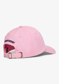 Pink adjustable baseball cap with brass buckle and embroidered "Superdry" text on the back, shown from a slight rear angle.