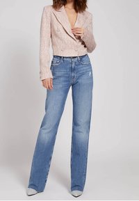 Blazer rosa cropped con texture e bottoni doppiopetto abbinato a jeans azzurri a vita alta. Silhouette aderente, leggero effetto consumato sui jeans.