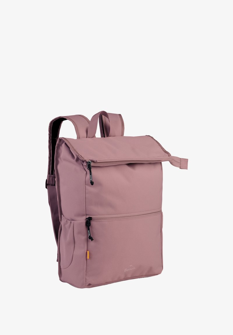 Pink fabric backpack with a roll-top closure, dual side zippers, two adjustable straps, and a front pocket. Smooth texture, minimalistic design.