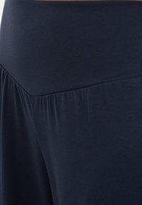 Gros plan sur un tissu bleu marine avec un détail de couture froncée créant un motif texturé subtil.