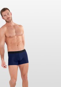 Námořnické boxerky s černým pasem se znakem, vyrobené z hladkého, pružného materiálu. Navrženy pro komfort a pohodlné nošení.