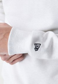 Hvid bomulds sweatshirt med ribbede manchetter. Broderet sort logo på venstre manchet. Blød tekstur med et afslappet fit design.