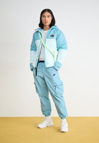 Nike Sportswear TECH WOVEN - Cargo trousers - denim turquoise/black