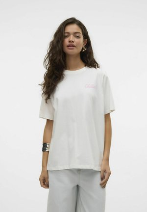 T-shirt en coton blanc à manches courtes, avec un texte « Chillin' » rose clair sur la poitrine. Associé à un pantalon en denim clair.