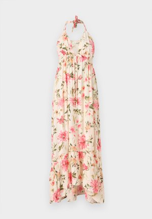 Robe maxi florale en crème avec des motifs de fleurs roses et vertes. Présente un décolleté halter et un ourlet à volants pour une silhouette fluide.