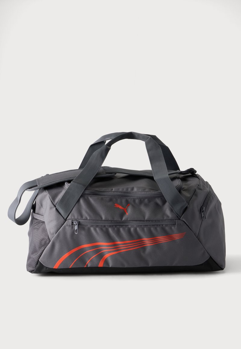 Γκρι τσάντα Puma τύπου duffel με μαύρες λαβές, μπροστινή τσέπη με φερμουάρ, δίχτυ πλαϊνή τσέπη και κόκκινο λογότυπο και ρίγες Puma στην μπροστινή πλευρά.