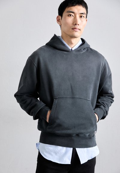 Sudadera gris oscuro de tela suave con bolsa tipo canguro, capucha con cordón y una camiseta ligera azul claro debajo. Diseño minimalista.