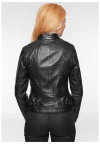 Schwarze Lederjacke mit taillierter Passform, Schulterpolstern, vertikalen Nahtdetails und Druckknopfakzenten an der Taille.