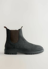 Zwarte suède Chelsea-boot met een bruin elastisch zijpaneel en trekband. Rubberen zool met profiel voor grip. Klassiek rond teenontwerp.
