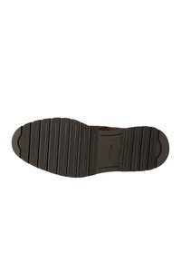 Bruine leren schoen met een getextureerde rubberen zool die horizontale groeven heeft en een ronde neus. De onderkant heeft een logo-afdruk.