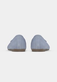 Ανοιχτό μπλε παπούτσια χωρίς κορδόνια με λεία σουέντ υφή και καφέ λαστιχένια σόλα σε αντίθεση. Ραφές κατά μήκος της φτέρνας και των πλευρών.