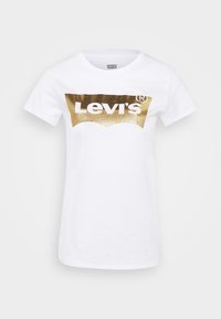 Biały bawełniany t-shirt z dużym złotym brokatowym logo Levi's na piersi, okrągłym dekoltem i krótkimi rękawami.