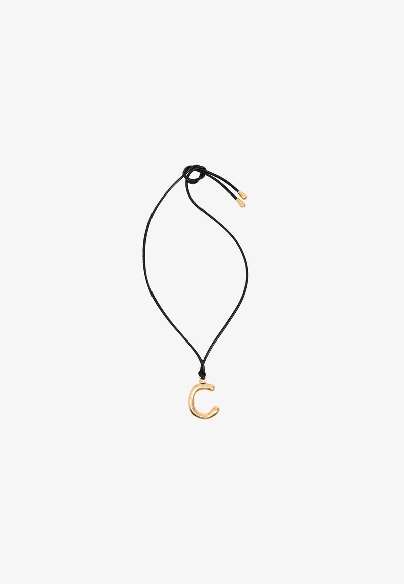 Kuldne metallist kaelakee "C" ripats mustal paelal, millel on reguleeritavad libisnõelad, sile pind ja minimalistlik disain.