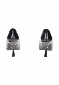 Scarpe nere in vernice con tacco alto e punta affusolata, decorate con dettagli a occhiello e un sottile tacco a stiletto.