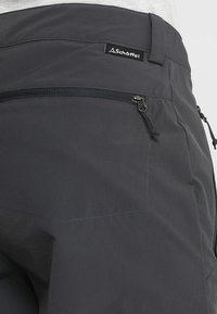 Pantalones exteriores grises fabricados en material ligero. Cuentan con un bolsillo con cremallera, cinturilla elástica y costuras reforzadas para mayor durabilidad.