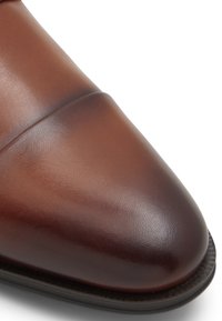 Brune læder dress sko med spidse tå, med glat tekstur og synlige syninger nær overdelen. Lavprofil gummisål.