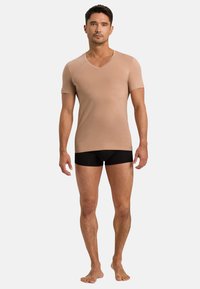 Jasnobrązowy, krótki rękaw, koszulka typu V-neck wykonana z miękkiego materiału, zestawiona z czarnymi szortami bokserskimi. Prosty design i dopasowany krój.