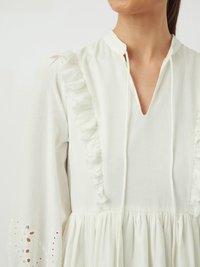 Rochie albă cu accente volan la decolteu și la mâneci. Mâneci lungi cu detalii de broderie englezească la mansete. Material moale.