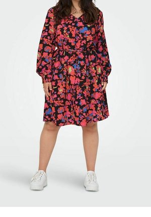 Sukienka w kwiaty z długimi rękawami, czarne tło, żywe czerwone, różowe i niebieskie kwiaty, dopasowana w talii, plisowana spódnica. Białe trampki.