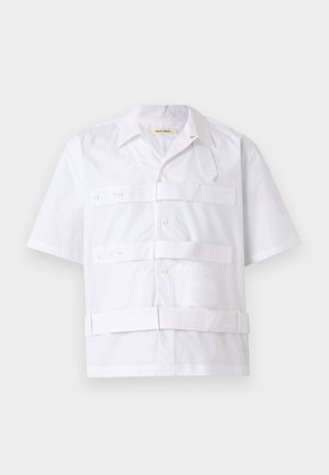 Chemise blanche à manches courtes avec boutons sur le devant, trois bandes horizontales au niveau de la poitrine et un col pointu.