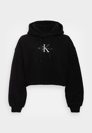 Zwarte cropped hoodie van zacht materiaal, met een grote capuchon, lange mouwen en een frontlogo in zilverdraad. Geribbelde manchetten en zoom.