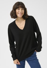 Pull noir à col en V avec des manches longues, fabriqué dans un matériau doux. Présente une coupe décontractée et des détails côtelés le long de l'encolure et de l'ourlet.