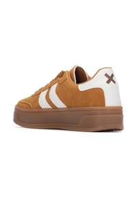 Zapatillas de ante marrón con acentos en cuero blanco, que cuentan con una suela de goma y tres franjas blancas en el lateral; detalle de suela exterior en marrón claro.