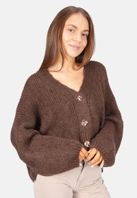 Brauner Strickcardigan mit V-Ausschnitt, übergroßen Ärmeln und dekorativen Knöpfen. Dicke Textur und lockere Passform.