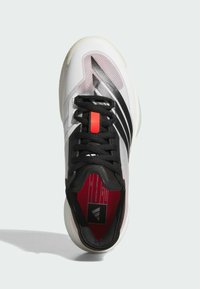 Scarpa da basket bianca e nera con tomaia in rete, accentuate da dettagli rossi e suola testurizzata. Il design presenta linee distintive e branding all'interno.