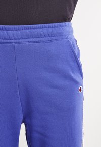 Blauwe katoenen joggers met een elastische tailleband, zijzakken en een klein geborduurd logo. Glad gevoel met een relaxte pasvorm.