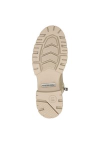 Suola di stivale beige con un motivo robusto, caratterizzata da tasselli spessi per una migliore aderenza e una placca metallica con il logo "G-STAR RAW".