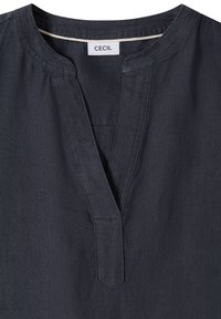 Chemise à manches longues gris foncé avec un col rond et une courte fente en V, étiquetée avec la marque « CECIL » à l'intérieur du col.