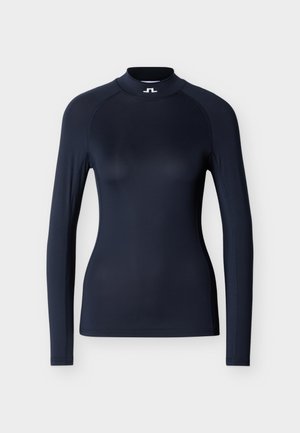 Top cu mâneci lungi de culoare bleumarin, realizat dintr-un material elastic, are un guler înalt, cusături plate și un design mulat cu mâneci raglan.