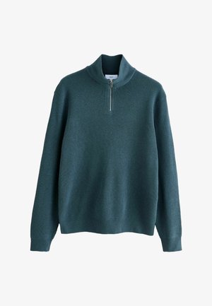 Grøn ribbet trøje med høj krave og lynlås til halvvejs, som har lange ærmer og et struktureret strikkemønster.