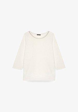 Bluză albă cu mâneci lungi, având un decolteu rotund, cu cusături accentuate argintii. Este fabricată dintr-un material moale, cu textură, având o croială lejeră.