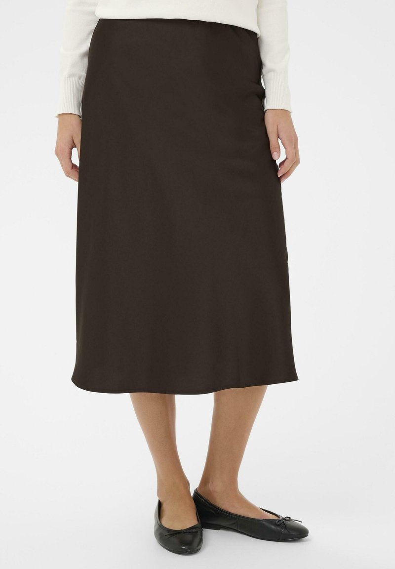 Falda midi marrón hecha de tejido suave, con una silueta recta y sutiles aberturas laterales, combinada con zapatos negros planos.