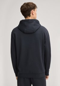 Felpa con cappuccio blu scuro dalla texture morbida, con polsini e orlo a coste. Presenta un cappuccio ampio e elementi di design senza cuciture sulla schiena.