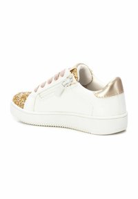 Zapatilla blanca con una puntera dorada brillosa, acento metálico dorado en el talón y cordones rosa claro. Suela de goma texturizada para mayor agarre.