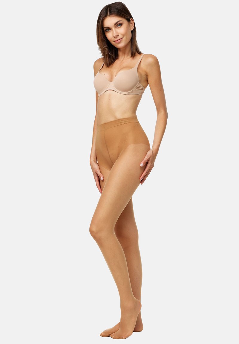 Sujetador beige acolchado y medias transparentes color bronce. Las medias tienen una textura suave y un diseño de cintura alta, ofreciendo un aspecto sin costuras en las piernas.