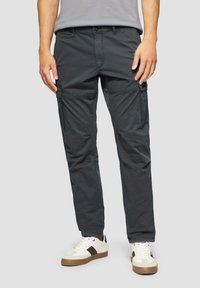 Donkergrijze cargobroek met zijzakken en een ontspannen pasvorm, gemaakt van een katoenmix. Draagt met witte sneakers en een grijs t-shirt.