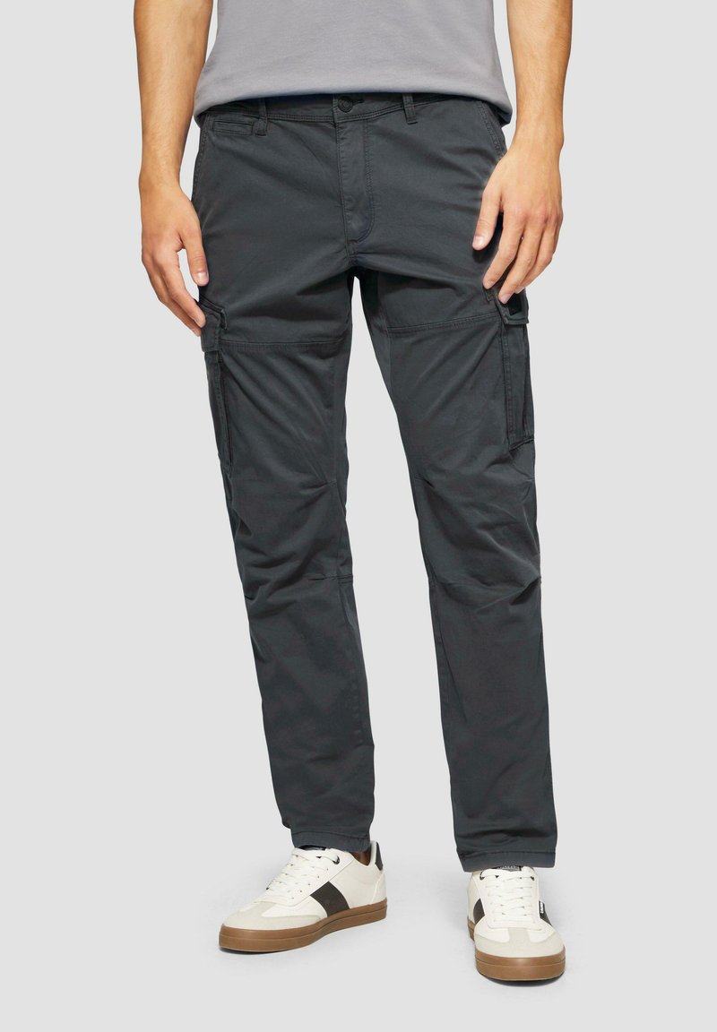 Donkergrijze cargobroek met zijzakken en een ontspannen pasvorm, gemaakt van een katoenmix. Draagt met witte sneakers en een grijs t-shirt.