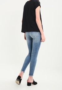 Mustat lyhythihaiset paidat, rento malli, yhdistetty vaaleansinisiin skinny-farkkuihin. Mustat avopäälliset, korkokengät, joissa on hopeinen yksityiskohta.