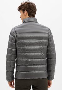Graue Daunenjacke mit glatter, glänzender Textur, horizontalen Nähten, hohem Kragen und elastischen Bündchen, entworfen für Wärme und Komfort.