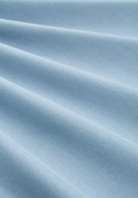 Heller blauer Stoff mit glatter Textur, der weiche Falten und einen subtilen Glanz zeigt. Keine sichtbaren Muster oder Hardwaredetails.