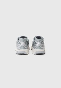 Helles graue Sport Schuhe mit Netzgewebe, strukturierten Akzenten und weißen Gummisohlen. Sie verfügen über ein schlankes Design mit einer niedrigen Silhouette.