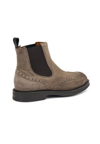 Bota Chelsea de ante marrón con paneles laterales elásticos, detalles de brogue, un tirador y una suela de goma plana. Textura suave en toda la bota.